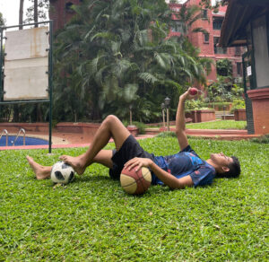 Aryan posing with a football, basketball and a cricket ball in his hand.